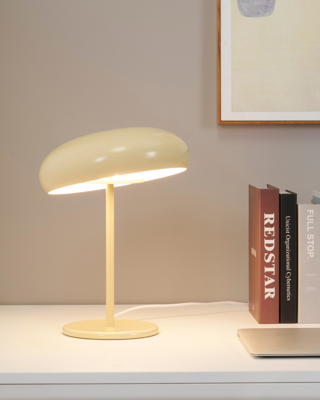 Yellow table lamp on a surface with books in the background