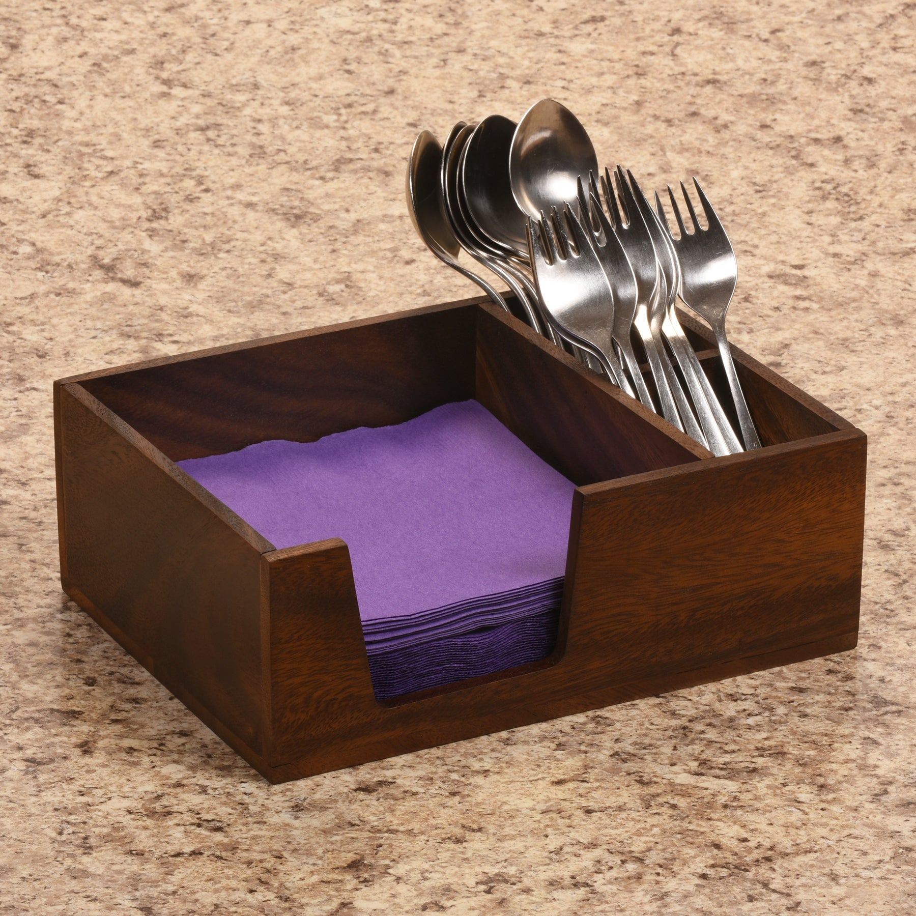 Wooden utensil holder with silverware and purple napkins on a marble surface