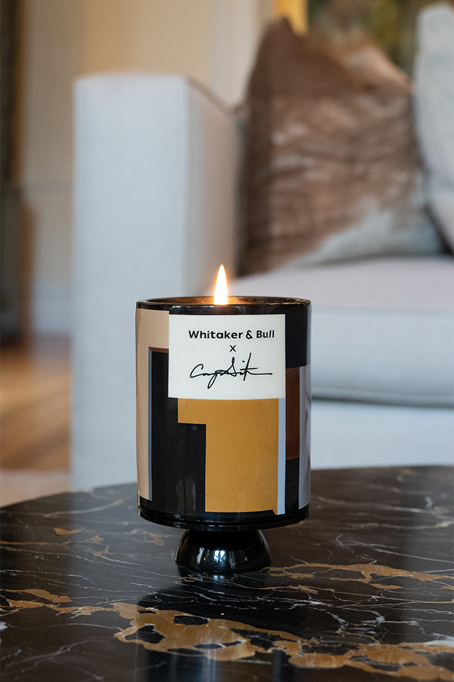 Candle with a label on a marble surface, blurred background