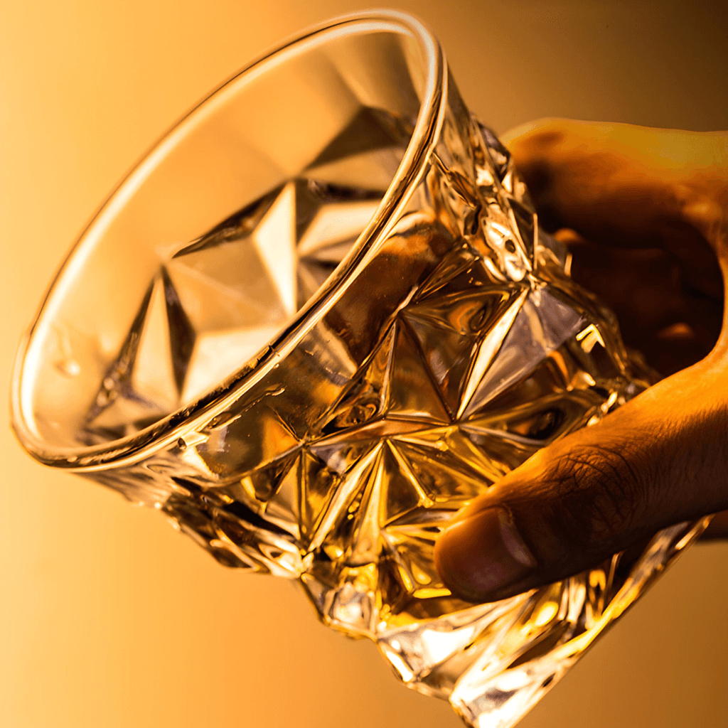 Hand holding a crystal glass with a warm glow on a yellow background