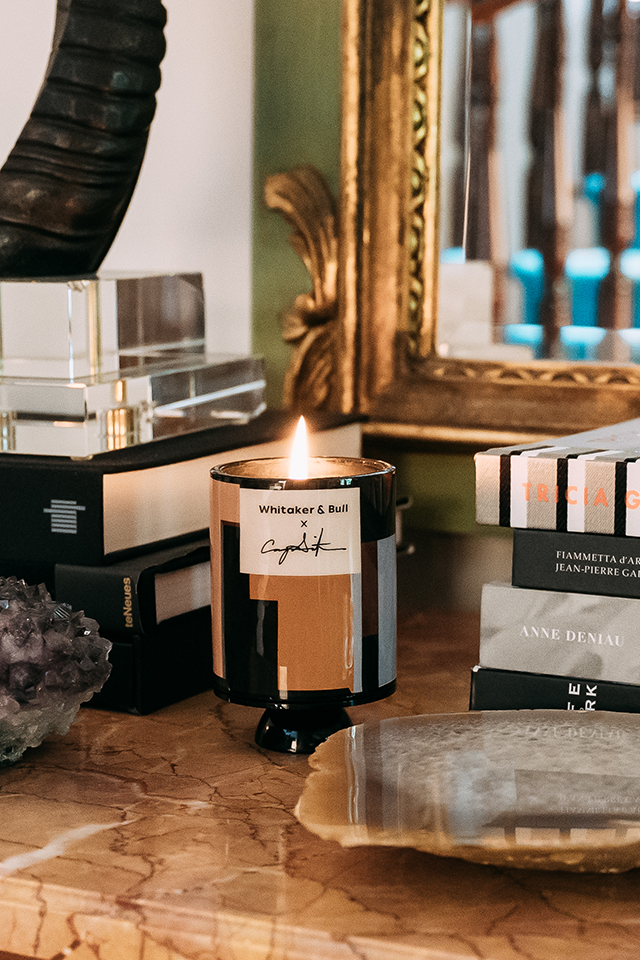 Candle with a decorative mirror and books in the background