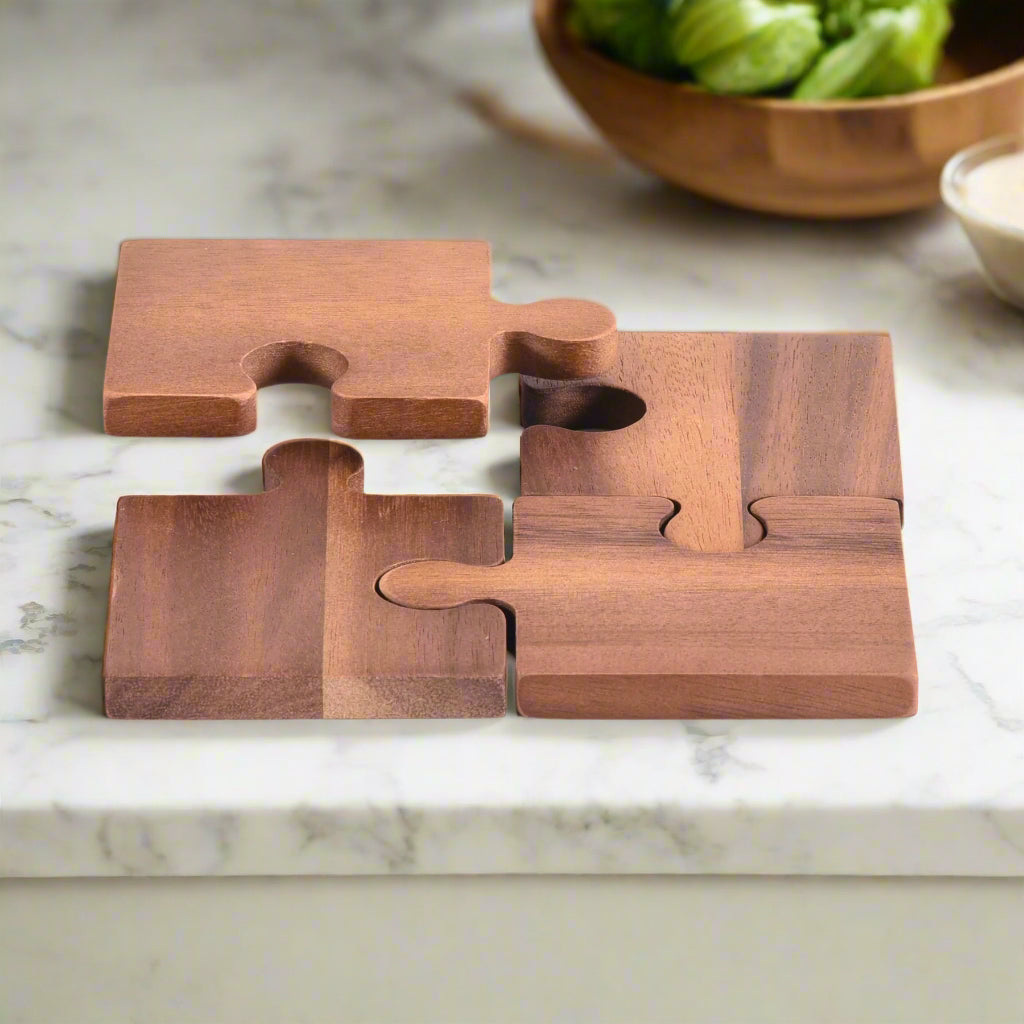 Wooden puzzle-style coasters on a marble surface with a bowl of greens in the background.