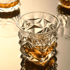 Crystal glass filled with amber liquid on a reflective surface