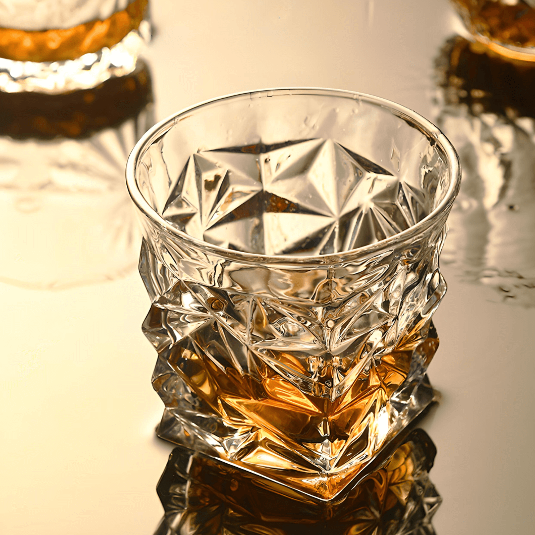 Crystal glass filled with amber liquid on a reflective surface