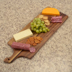 Wooden charcuterie board with cheese, grapes, and salami on a beige countertop