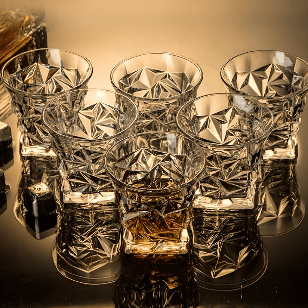 Set of crystal glasses with geometric patterns on a reflective surface.