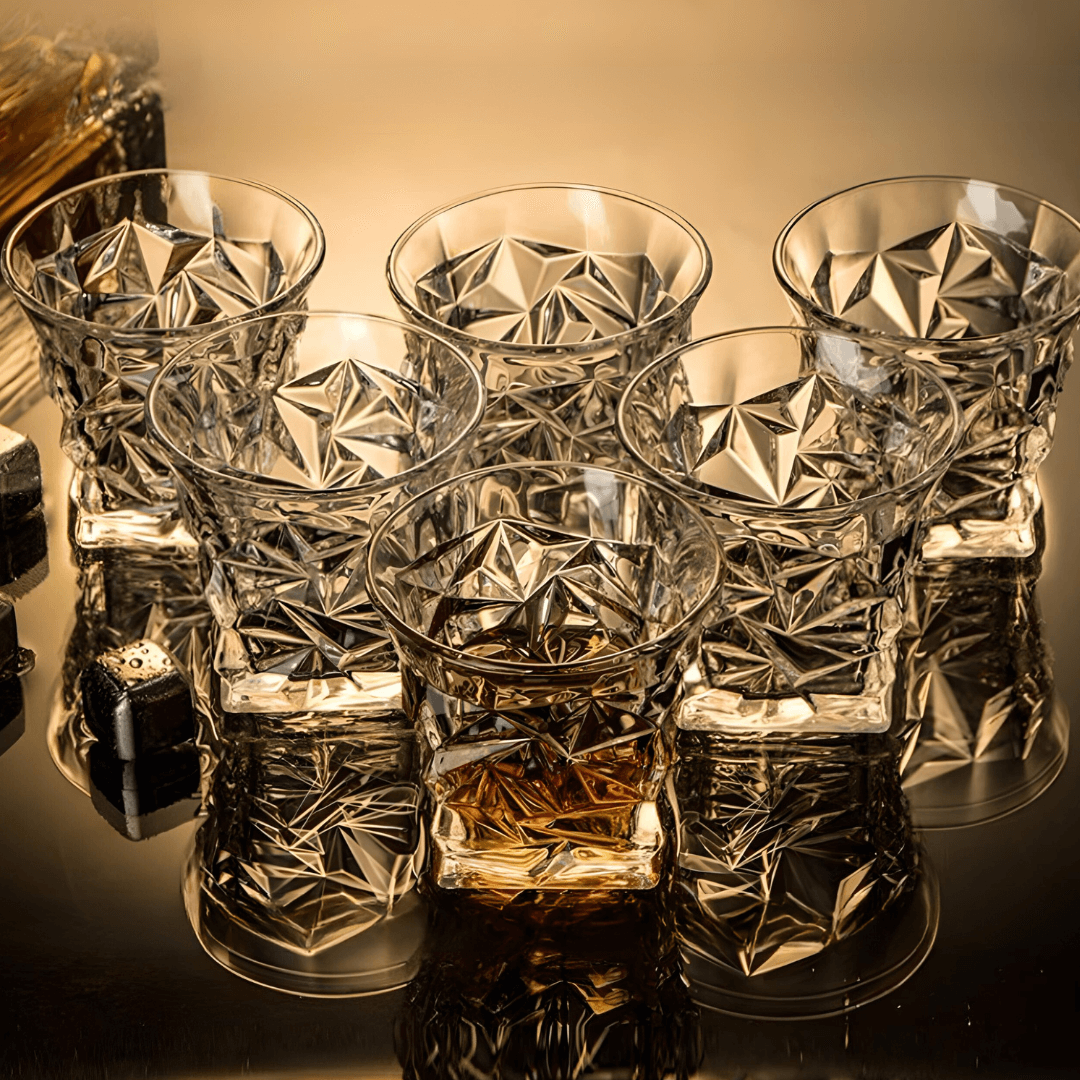 Set of crystal glasses with geometric patterns on a reflective surface.