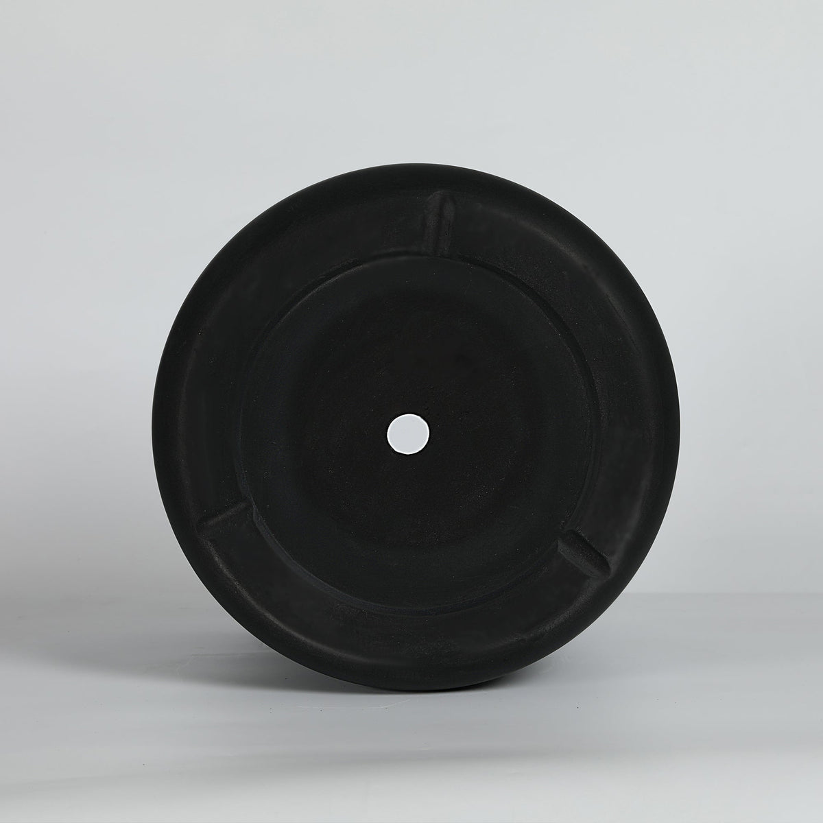 Black planter bottom with a hole on a light gray background