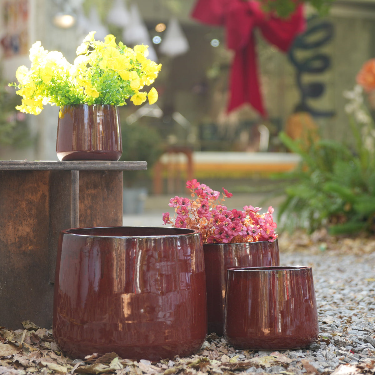 Set of brown ceramic planters with flowers on a garden setting