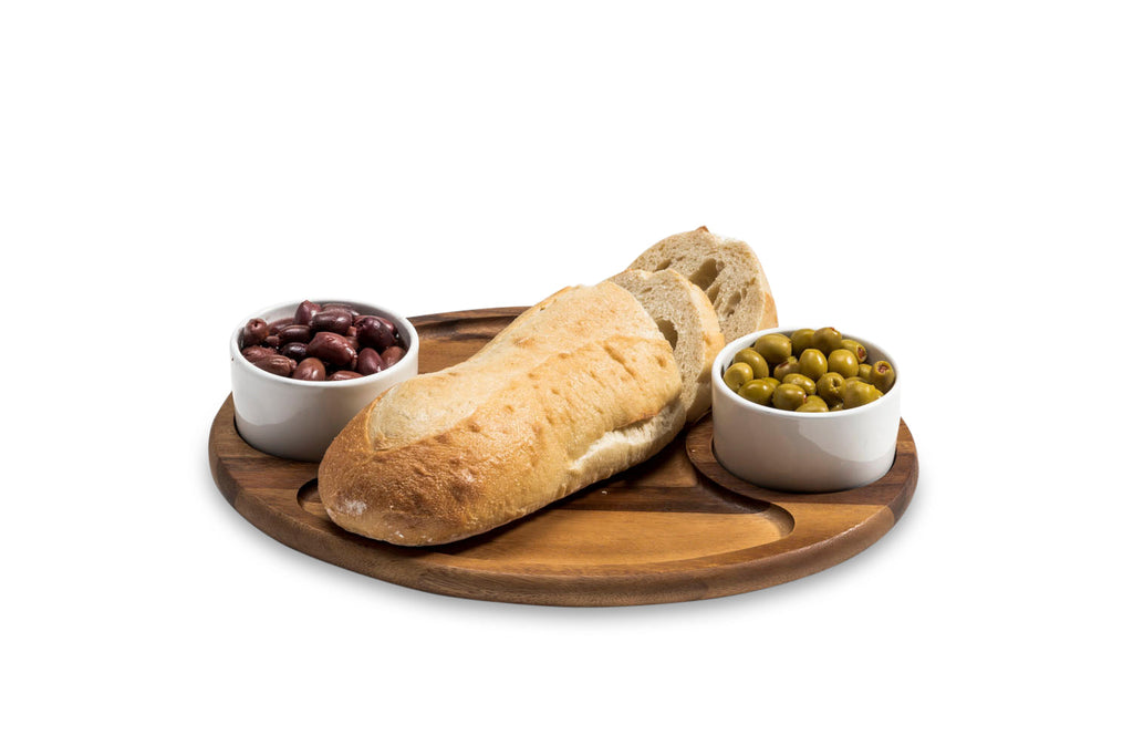 Wooden tray with a loaf of bread and two bowls of olives on a white background