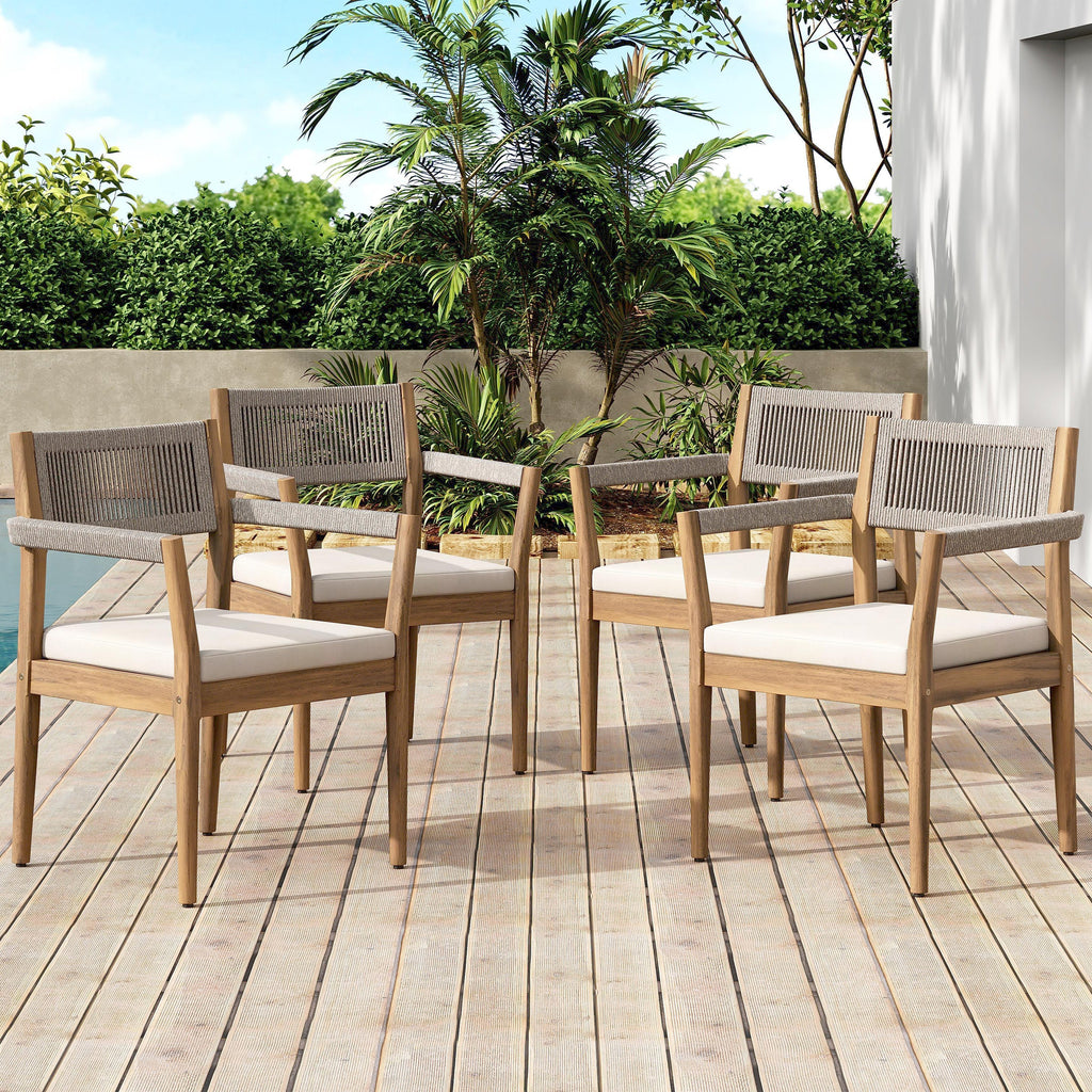 Set of four wooden outdoor chairs with white cushions on a wooden deck.