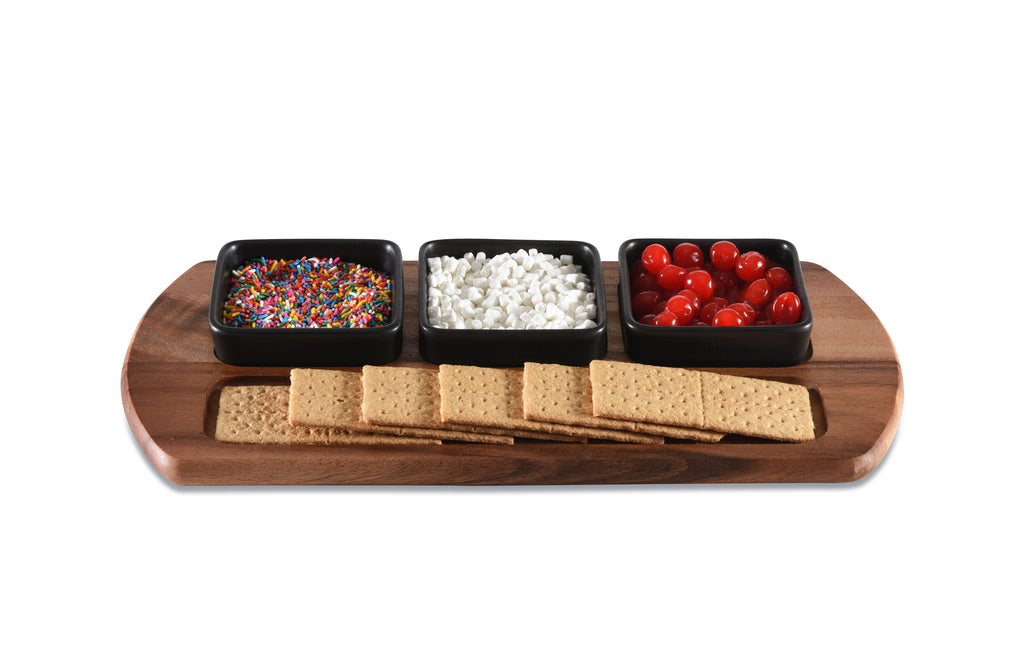 Wooden platter with crackers, sprinkles, white pearls, and cherry tomatoes on a white background