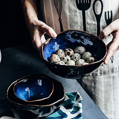 Hands holding large Amelia porcelain serving bowl with quail eggs — cobalt blue reactive glaze, organic form with smaller bowls below