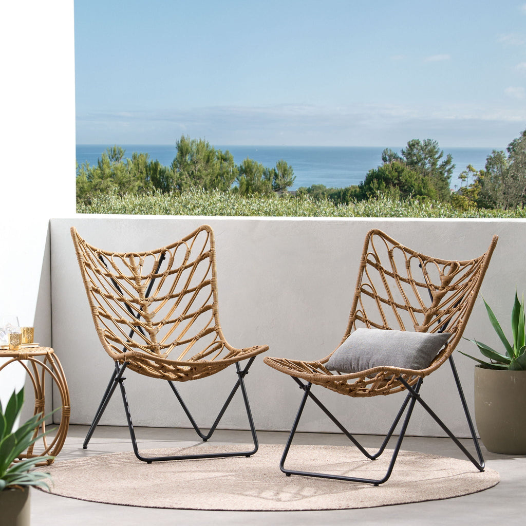 Two woven chairs with metal frames on a patio with ocean view
