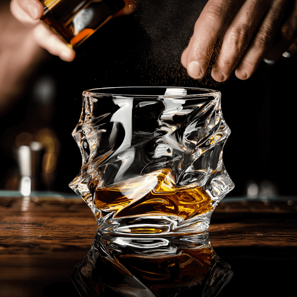 Person pouring whiskey into a textured glass on a wooden surface