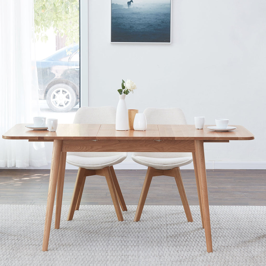 Dining room with wooden table and chairs, white rug, and framed picture on wall.