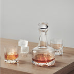 Glass decanter and glasses with liquid on a wooden surface