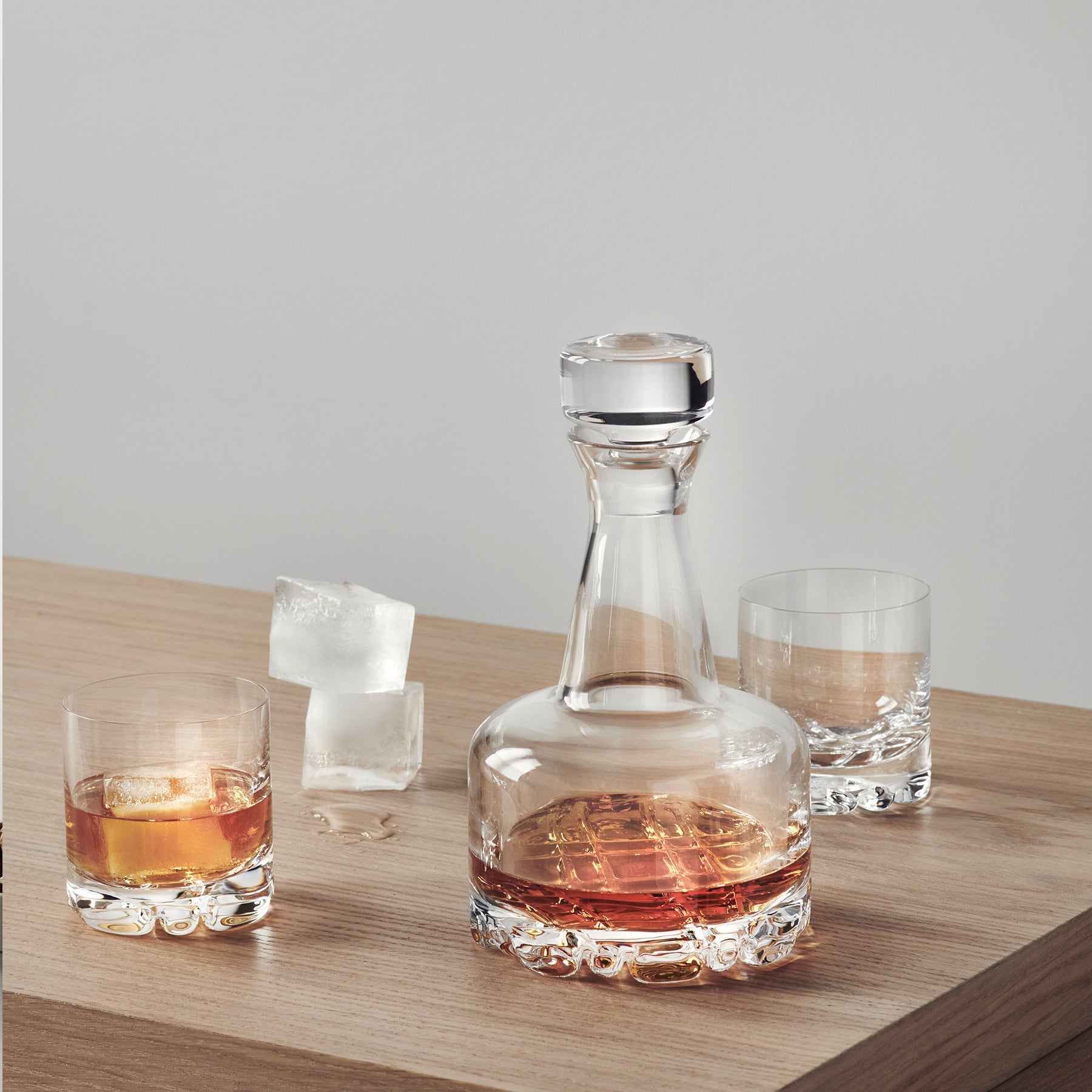 Glass decanter and glasses with liquid on a wooden surface