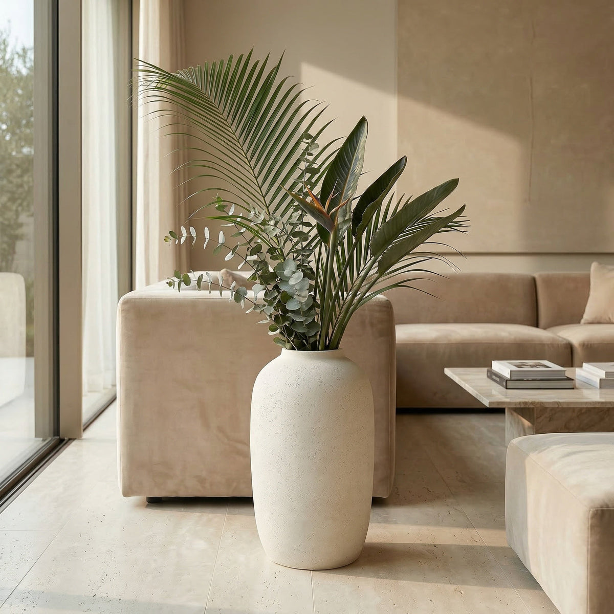 Modern living room with a beige sofa, coffee table, and a large plant in a white pot.
