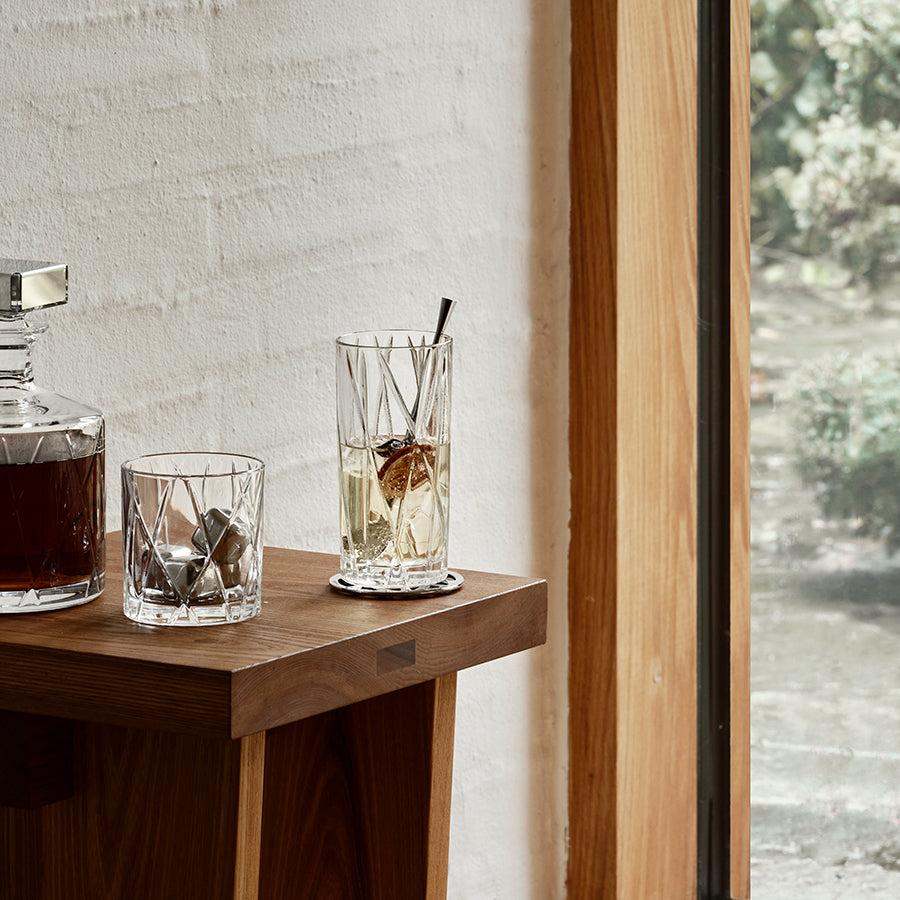 Two glasses with drinks on a wooden table next to a window.