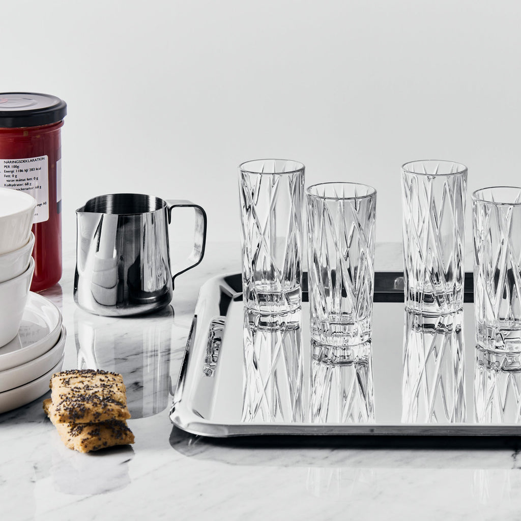 Set of crystal glasses on a tray with cookies and a container in the background
