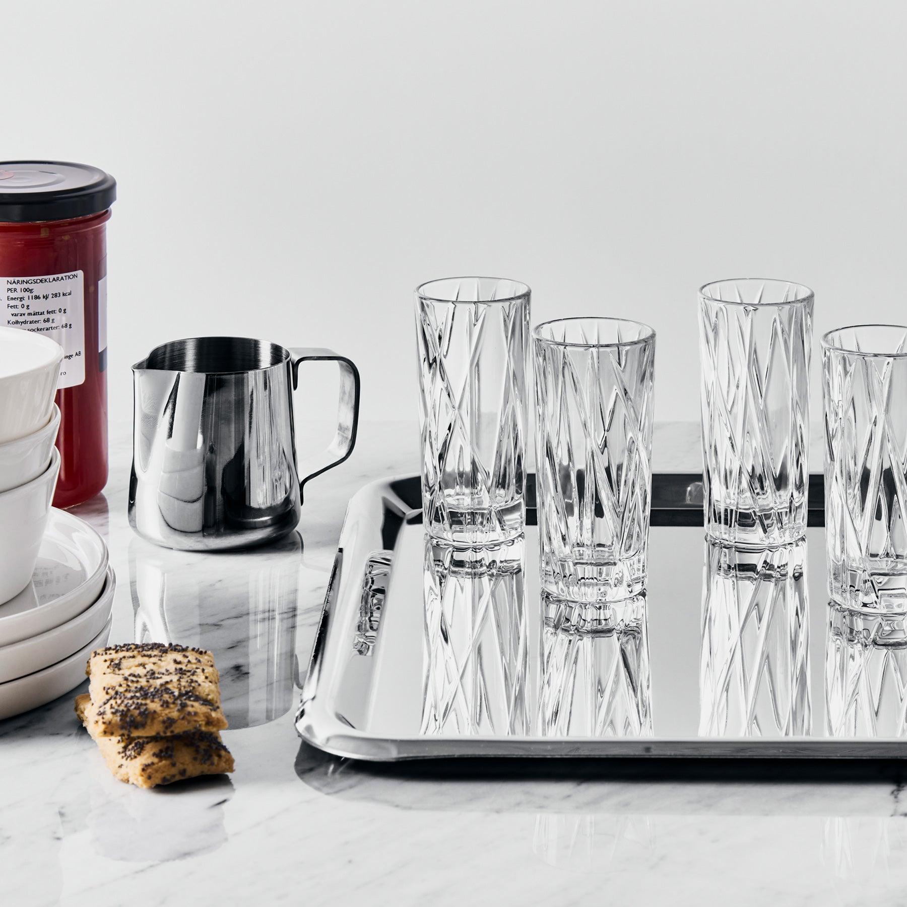 Set of crystal glasses on a tray with cookies and a container in the background