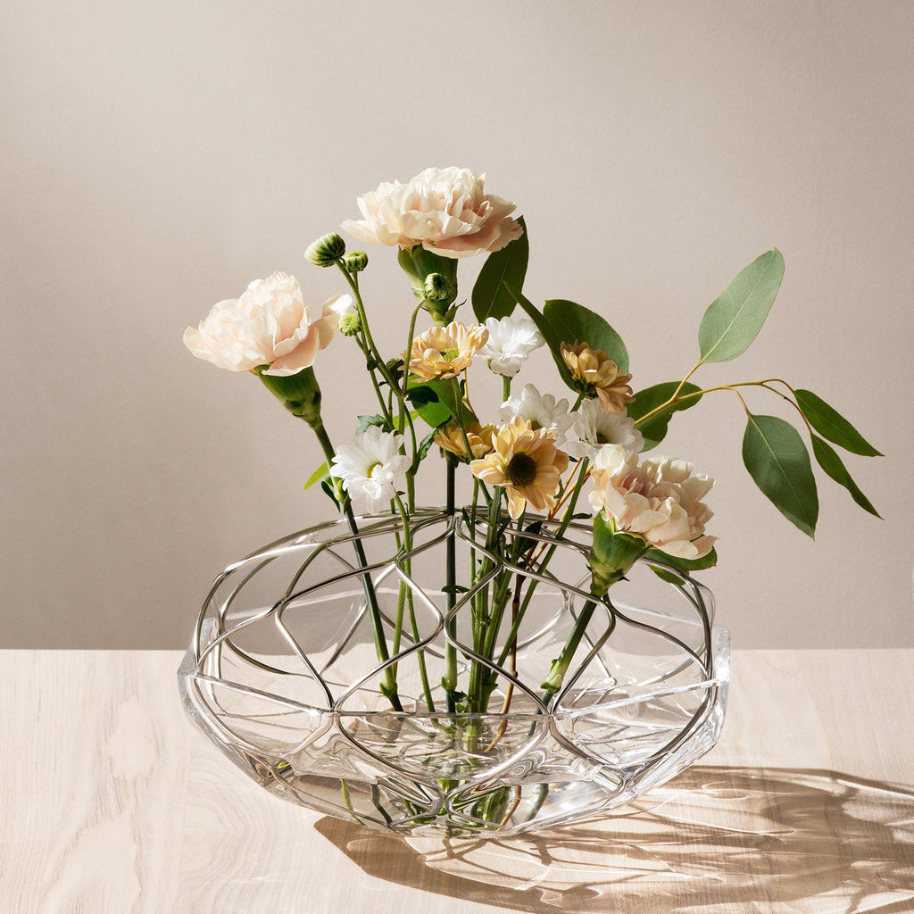 Clear glass vase with flowers on a light surface