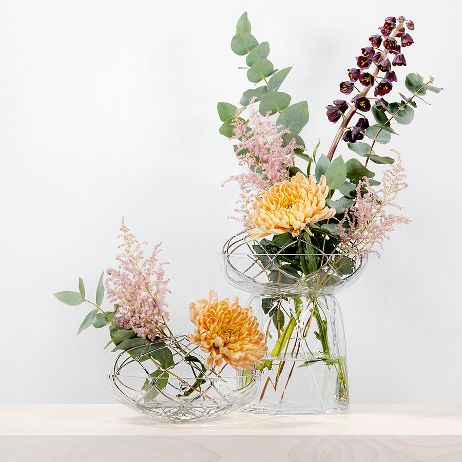 Two glass vases with floral arrangements on a white background
