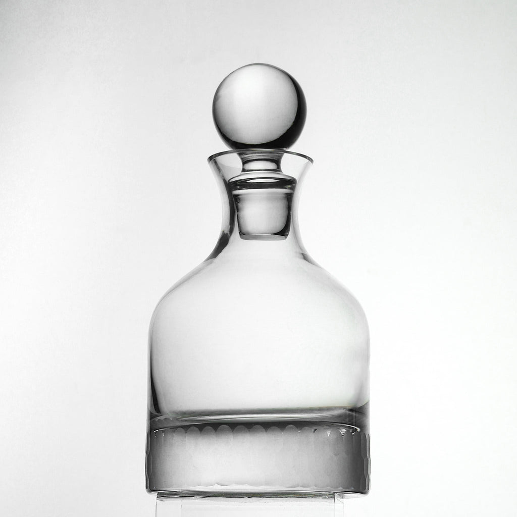 Clear glass decanter with a spherical stopper on a white background