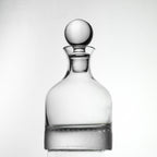 Clear glass decanter with a spherical stopper on a white background