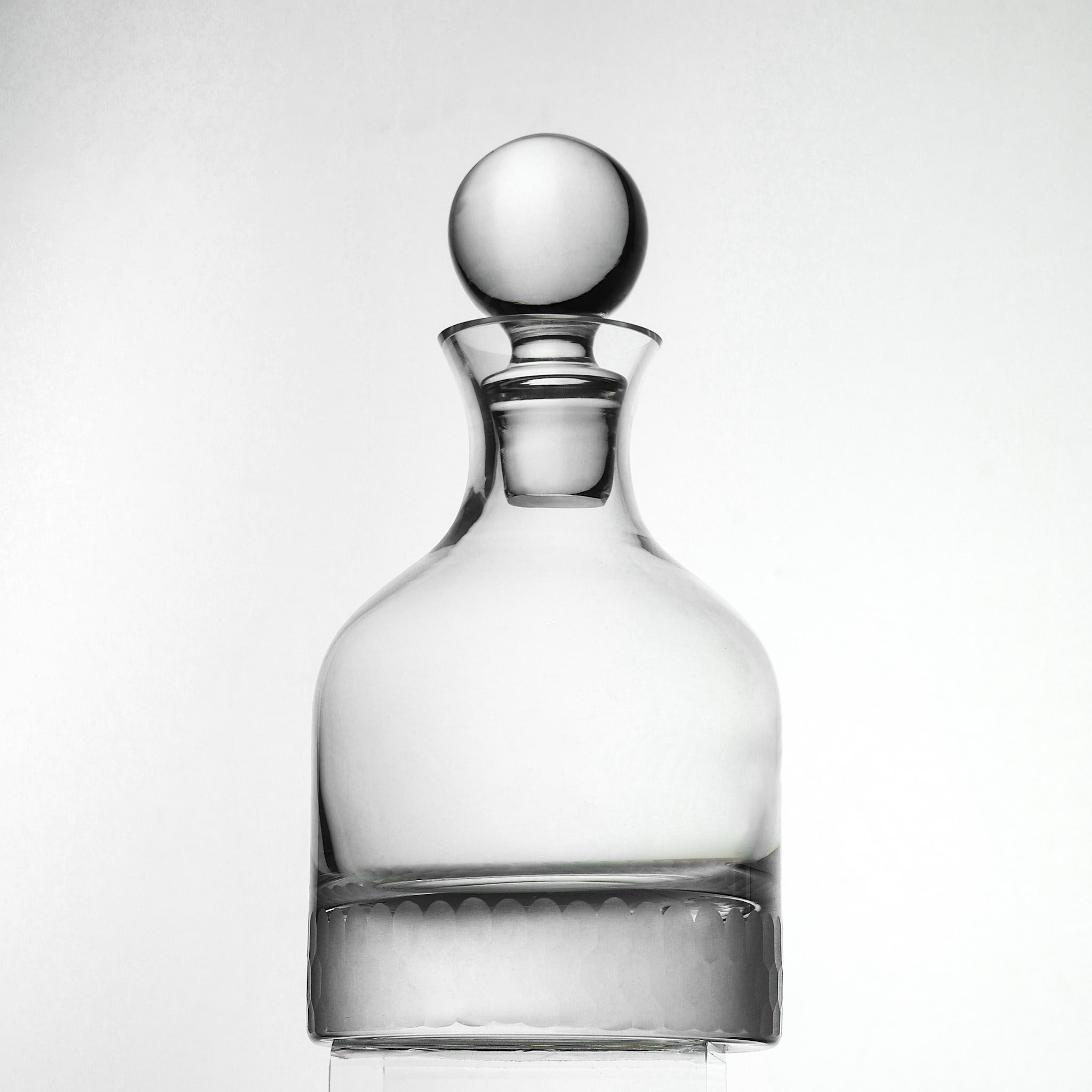 Clear glass decanter with a spherical stopper on a white background