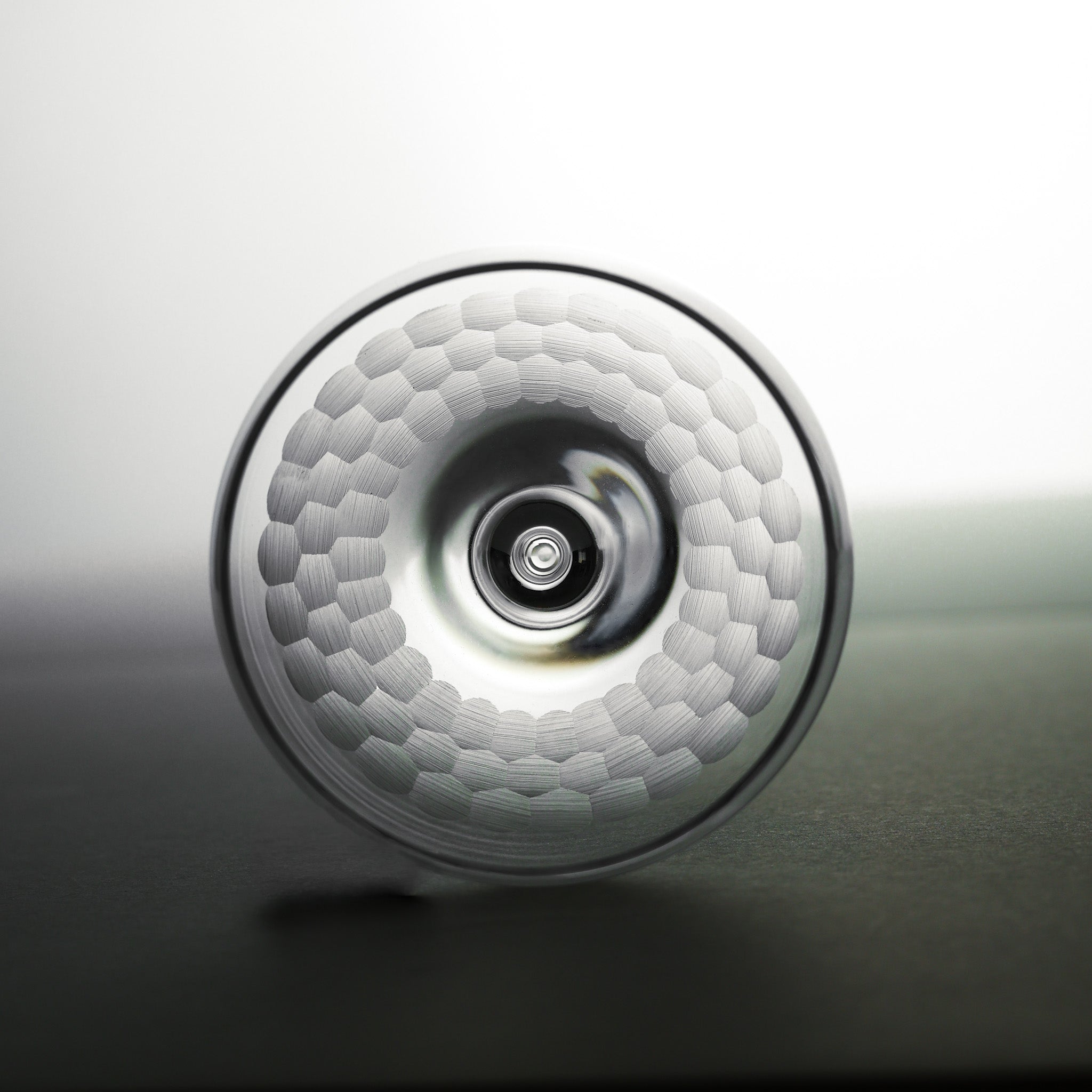 Close-up of a textured round glass with a central circular feature on a gradient background