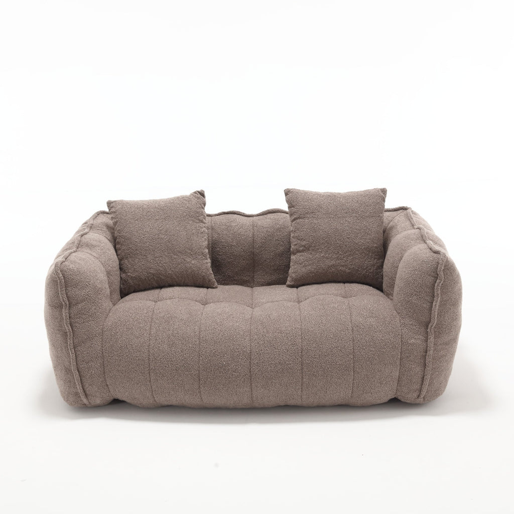 Brown sofa with quilted design and two cushions on a white background