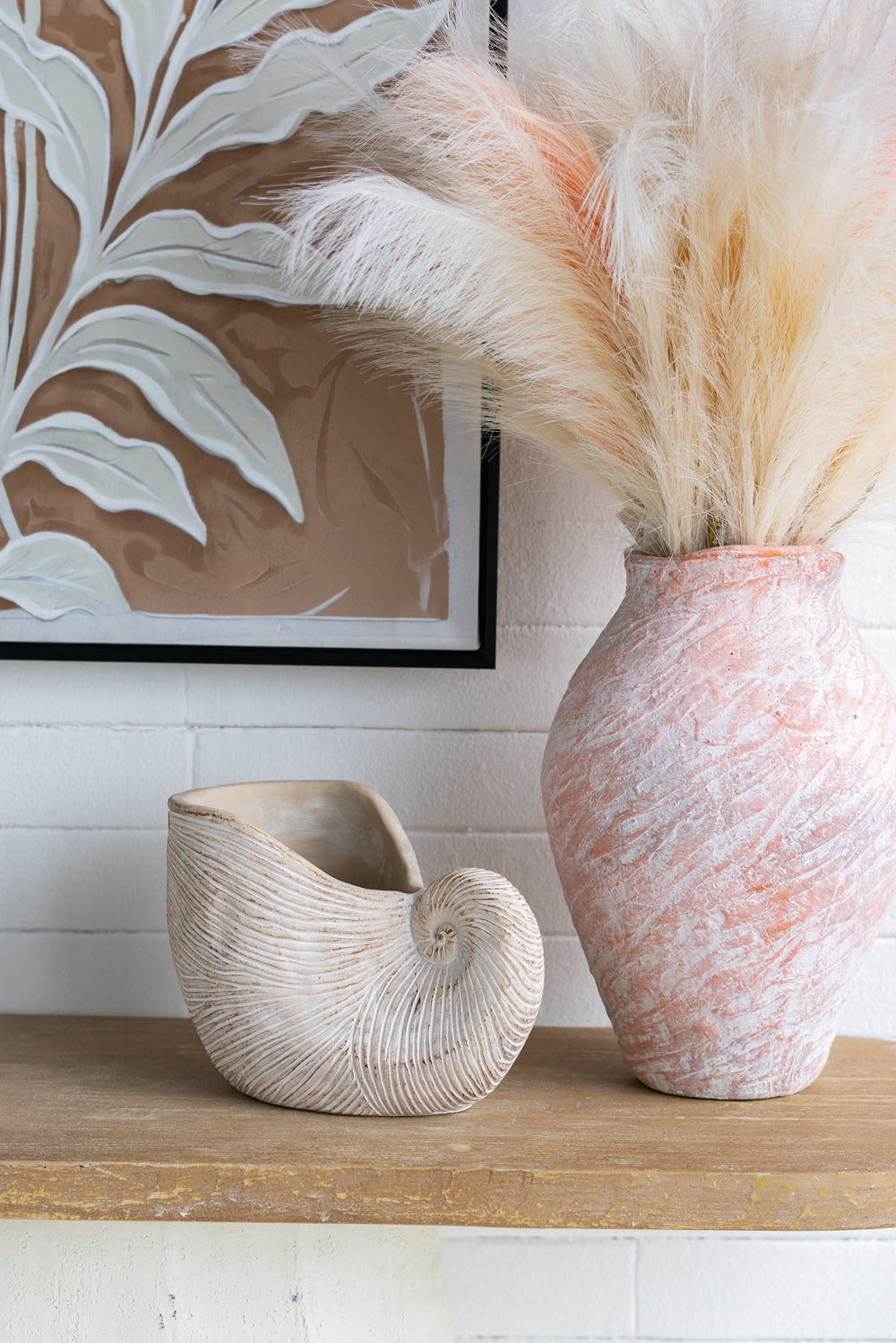 Decorative vases on a shelf with a framed artwork in the background