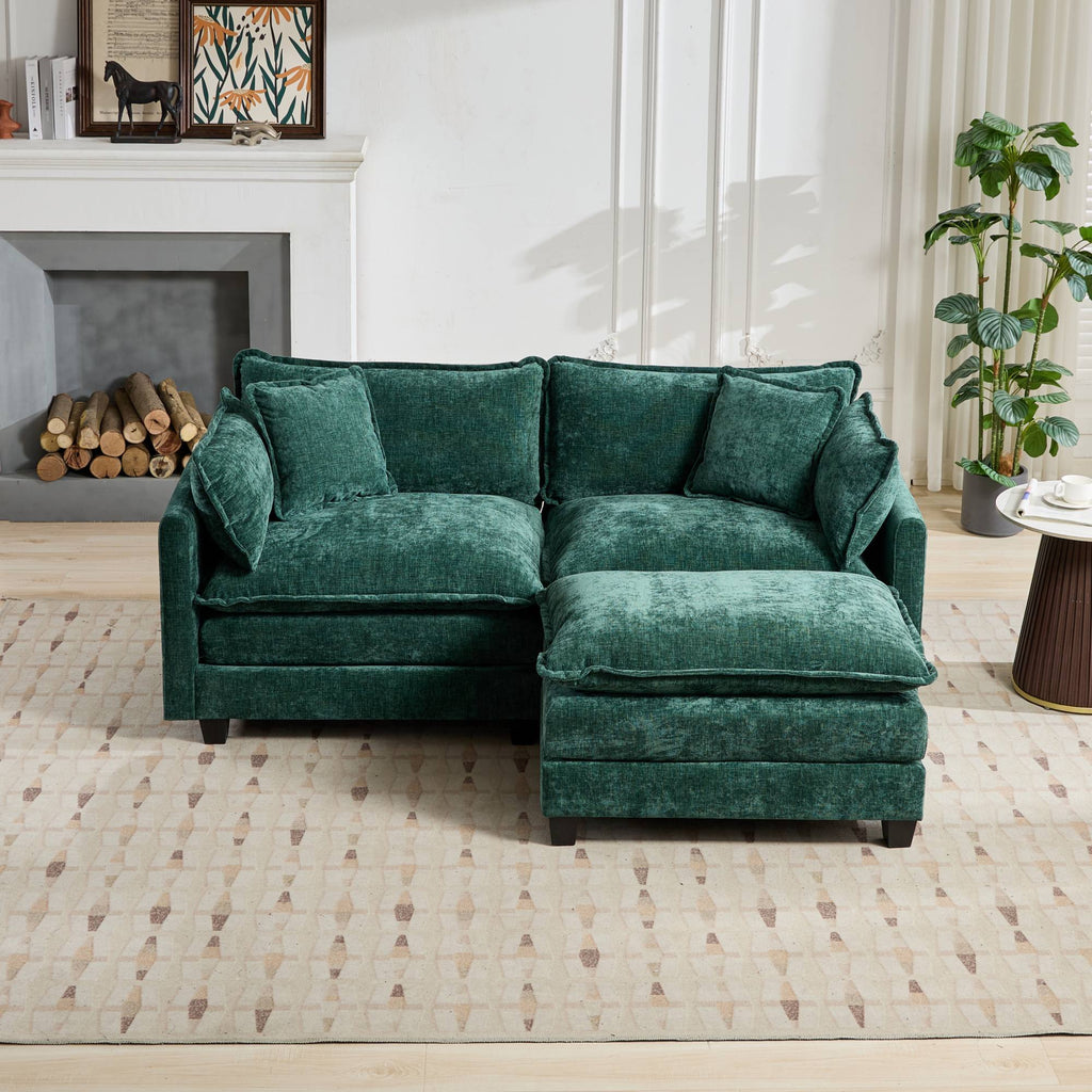 Green sectional sofa in a living room setting with a fireplace and plants.
