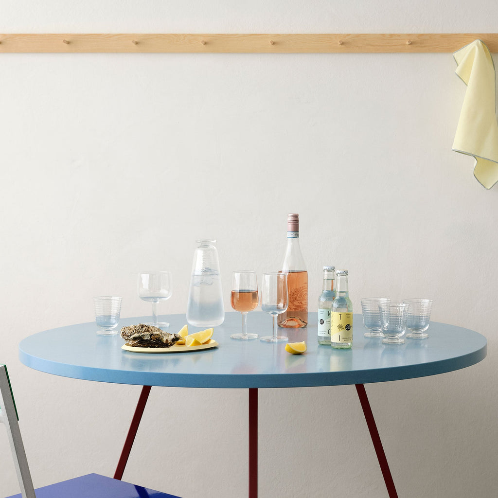 Round blue table with drinks and snacks on a white wall background
