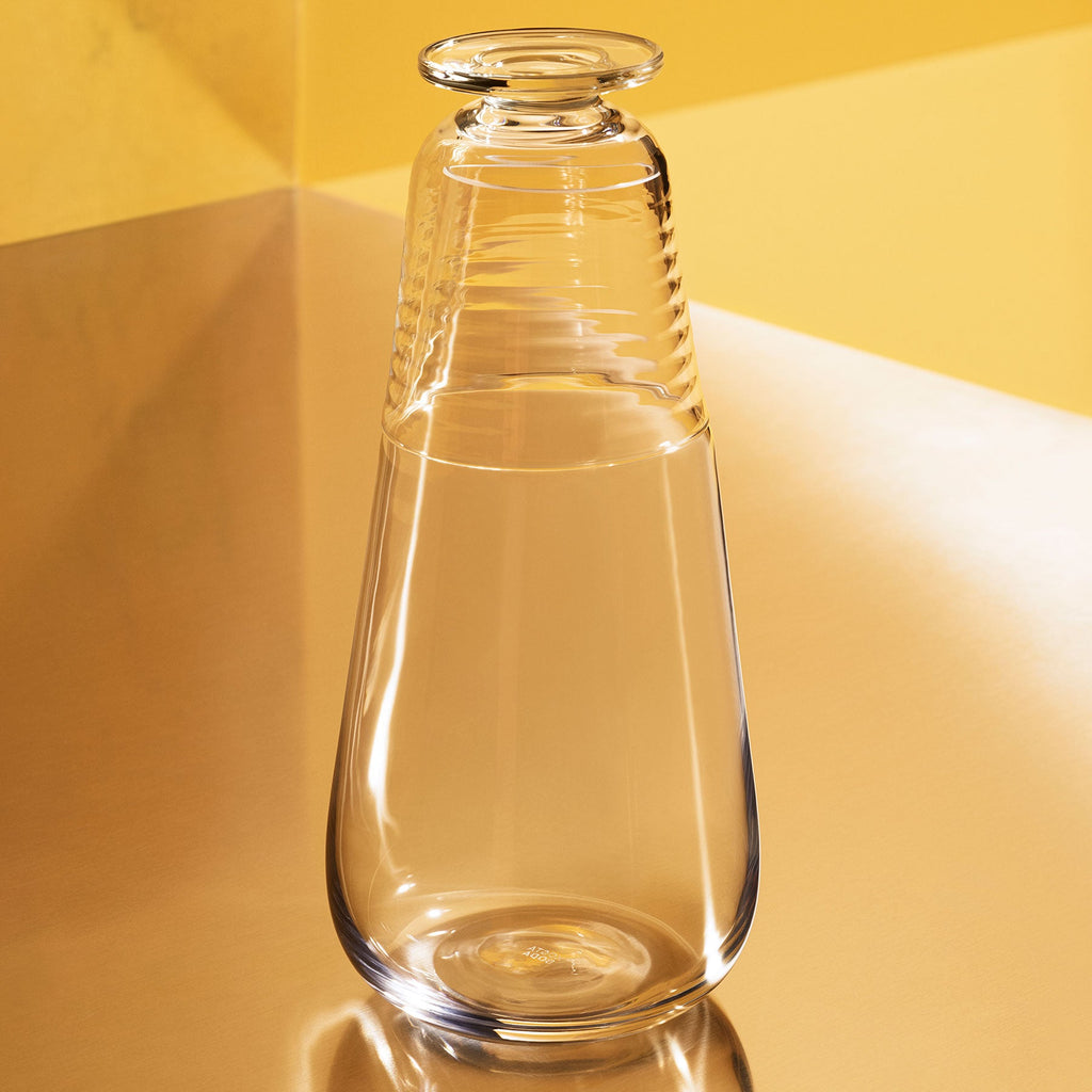 Clear glass carafe with glass lid on a yellow background