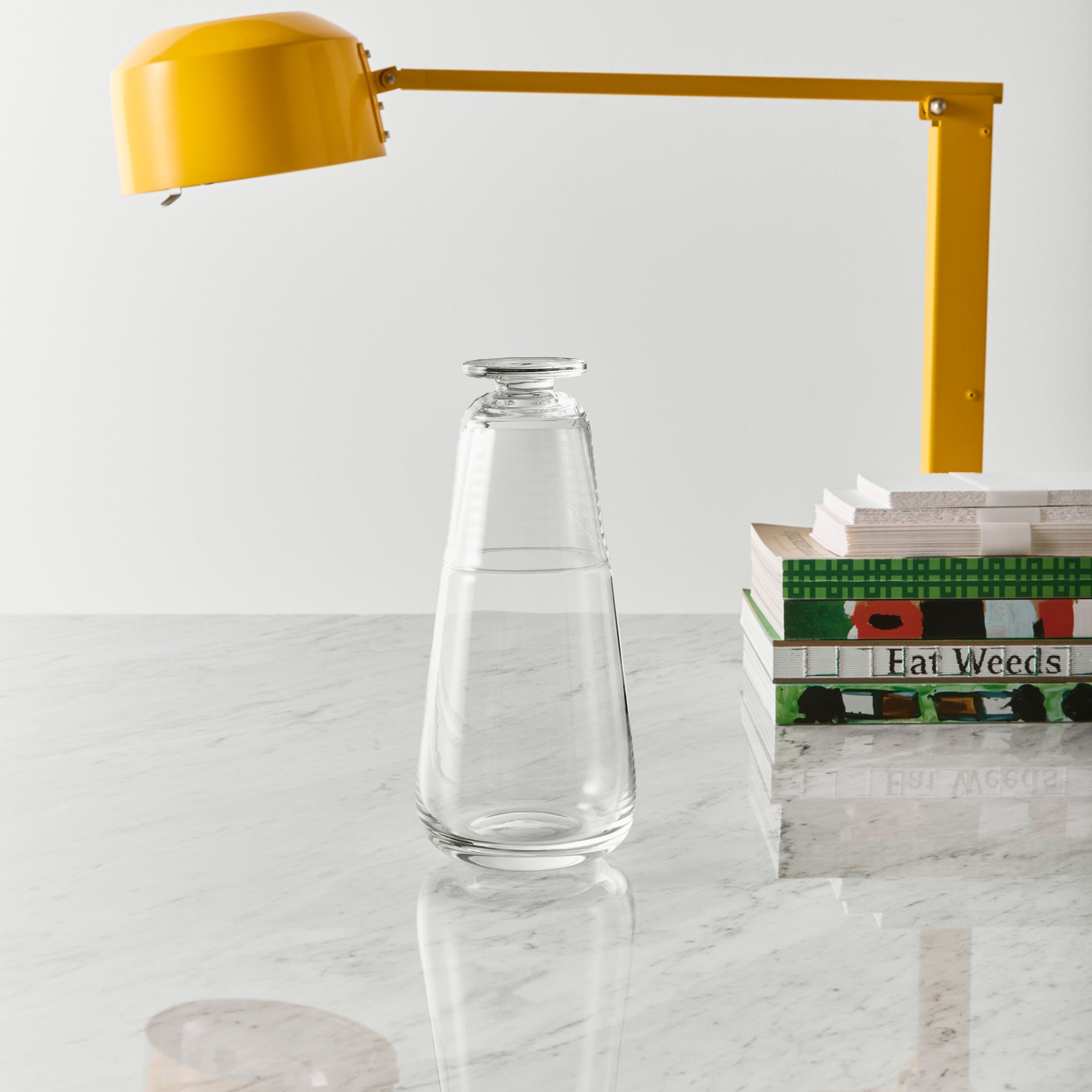 Clear glass carafe on a marble surface with a yellow lamp in the background