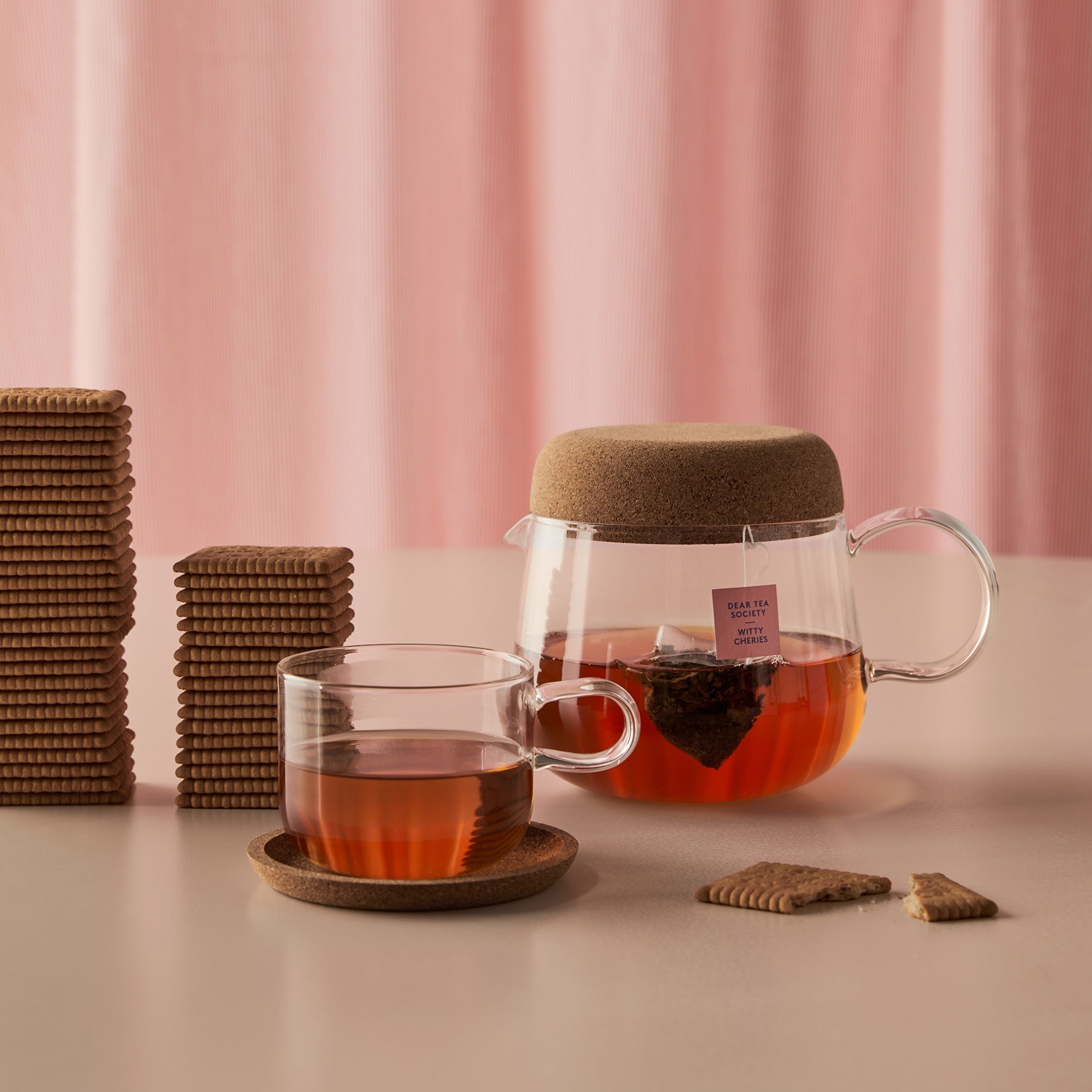 Tea set with glass mug and teapot on a pink background
