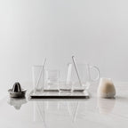 Set of glassware and kitchen tools on a marble surface with a light gray background