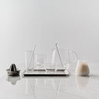 Set of glassware and kitchen tools on a marble surface with a light gray background