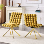 Two mustard yellow chairs with gold legs in a living room setting.