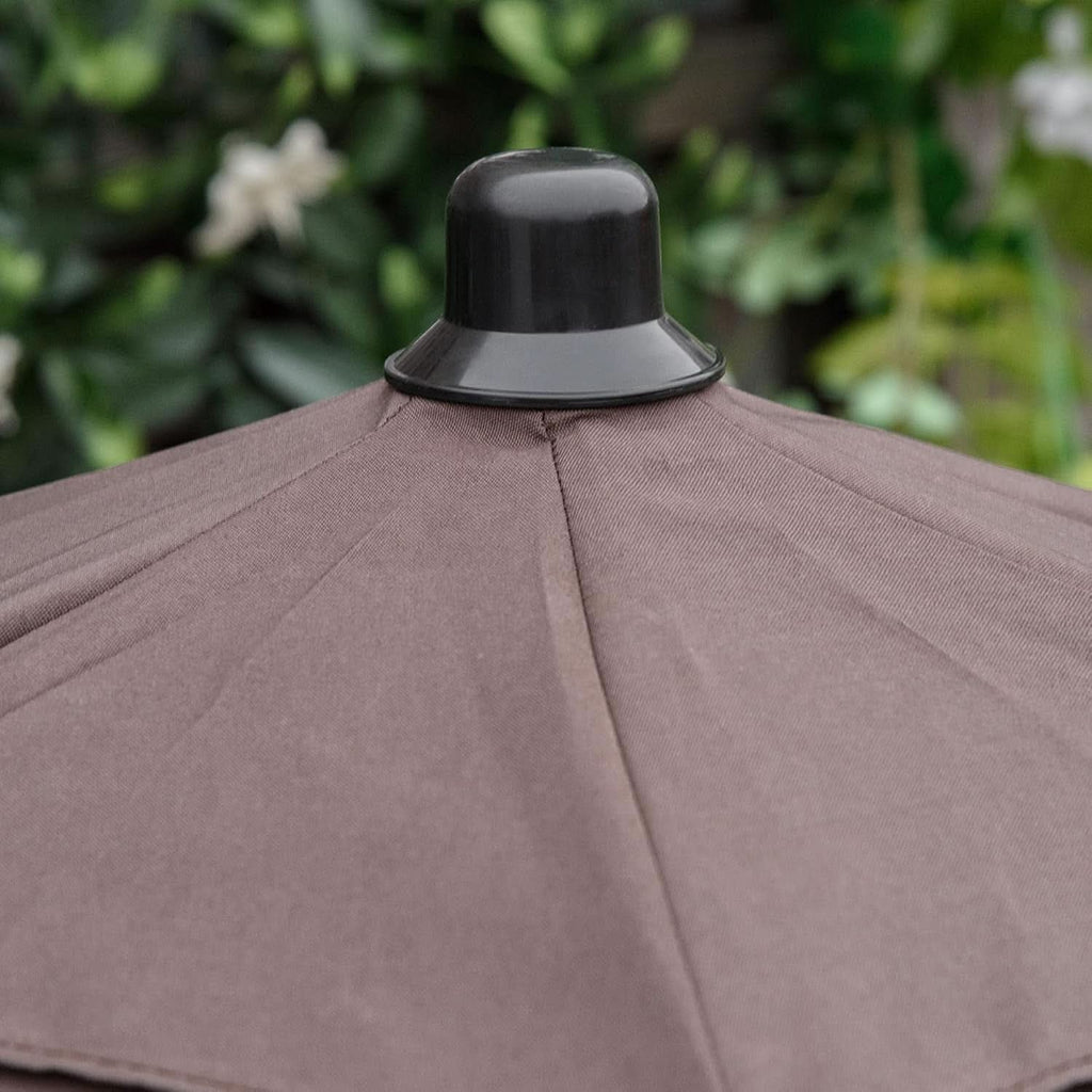 Close-up of a brown patio umbrella with a black canopy against a blurred green garden background