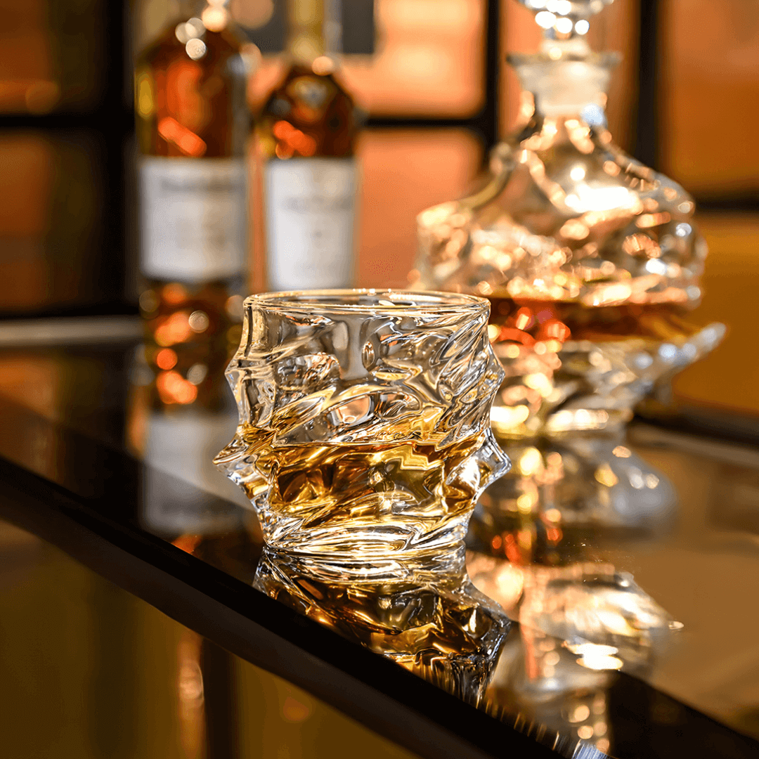 Clear glass whiskey glass with liquid on a bar counter, bottles in the background