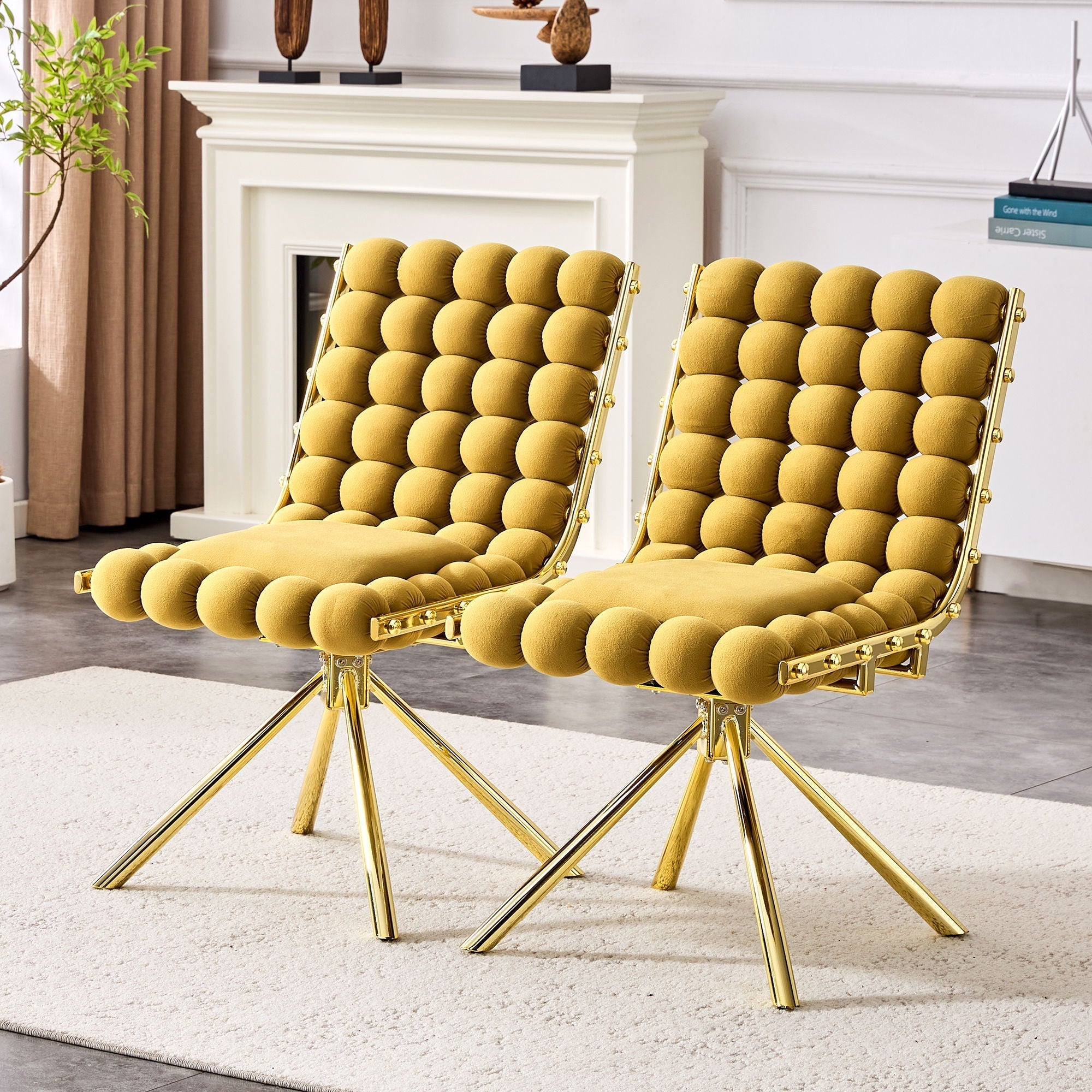 Two mustard yellow chairs with gold legs in a room with a fireplace and decor.