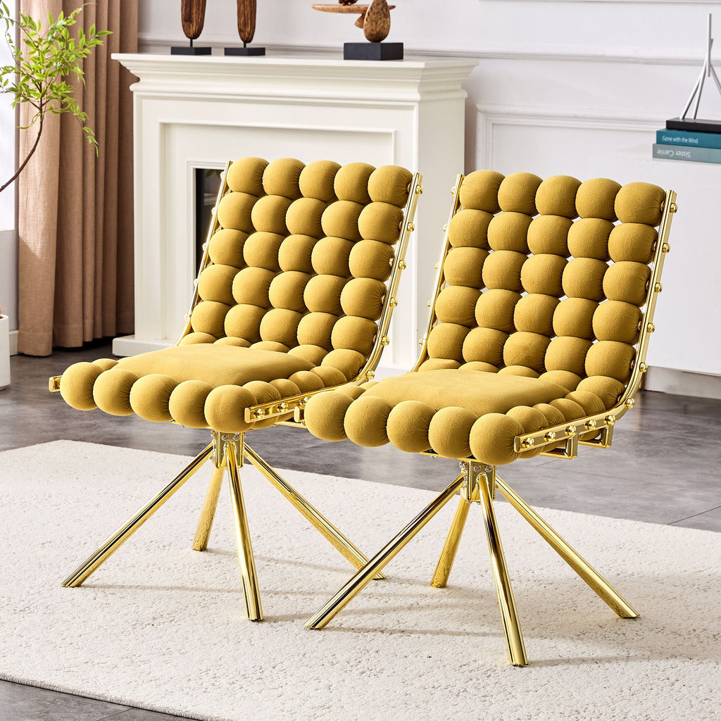 Two mustard yellow chairs with gold legs in a room with a fireplace and decor.
