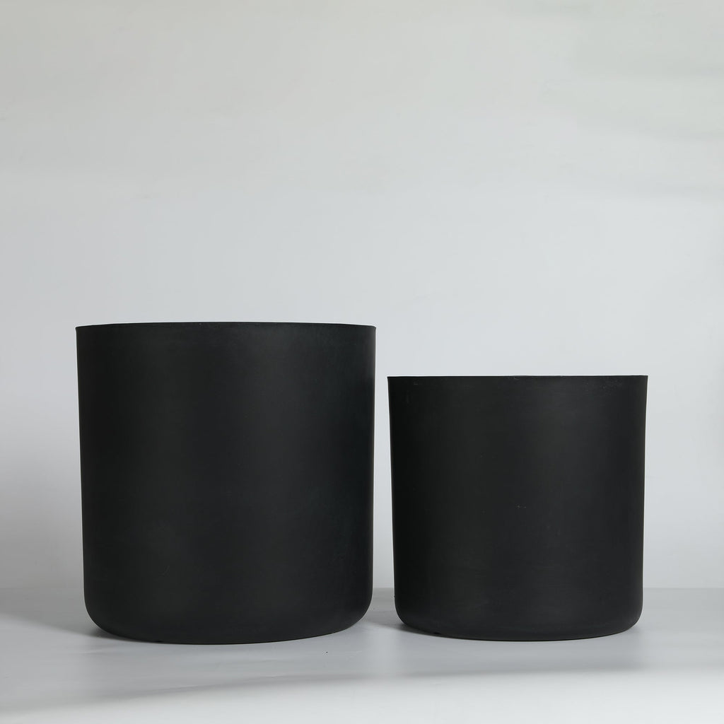 Two black cylindrical planters on a light gray background