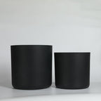 Two black cylindrical planters on a light gray background