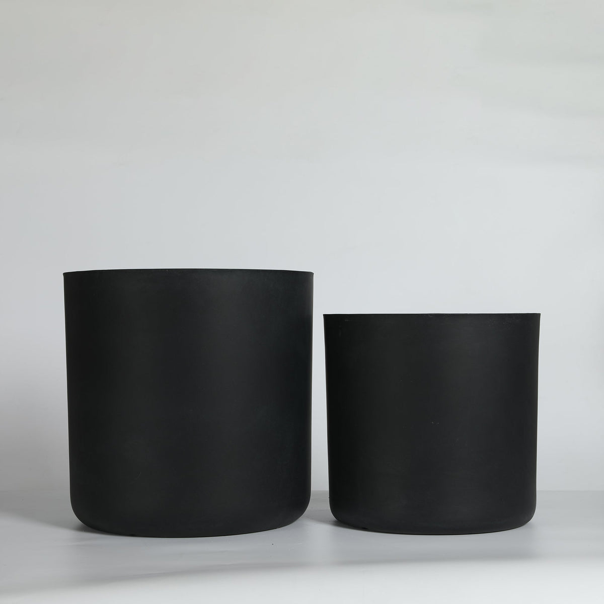 Two black cylindrical planters on a light gray background