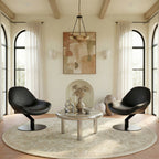 Modern living room with black chairs, round table, and abstract art on the wall.
